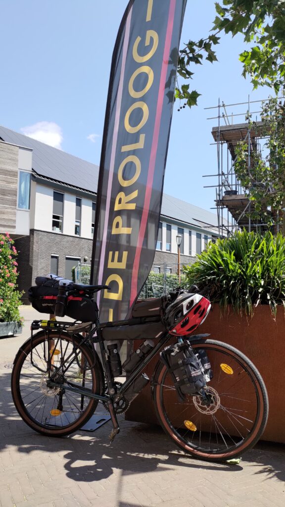 Un vélo équiper en bikepacking avec un drapeau du café De Proloog