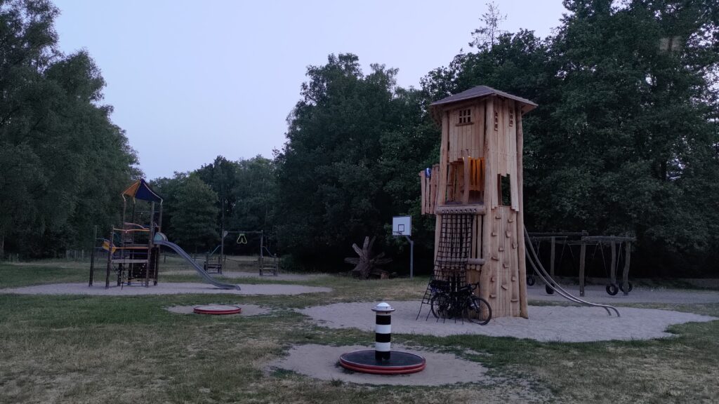 Vue d'ensemble d'un parc de jeux pour enfants avec notamment une tour de 4 étages avec un vélo au pied