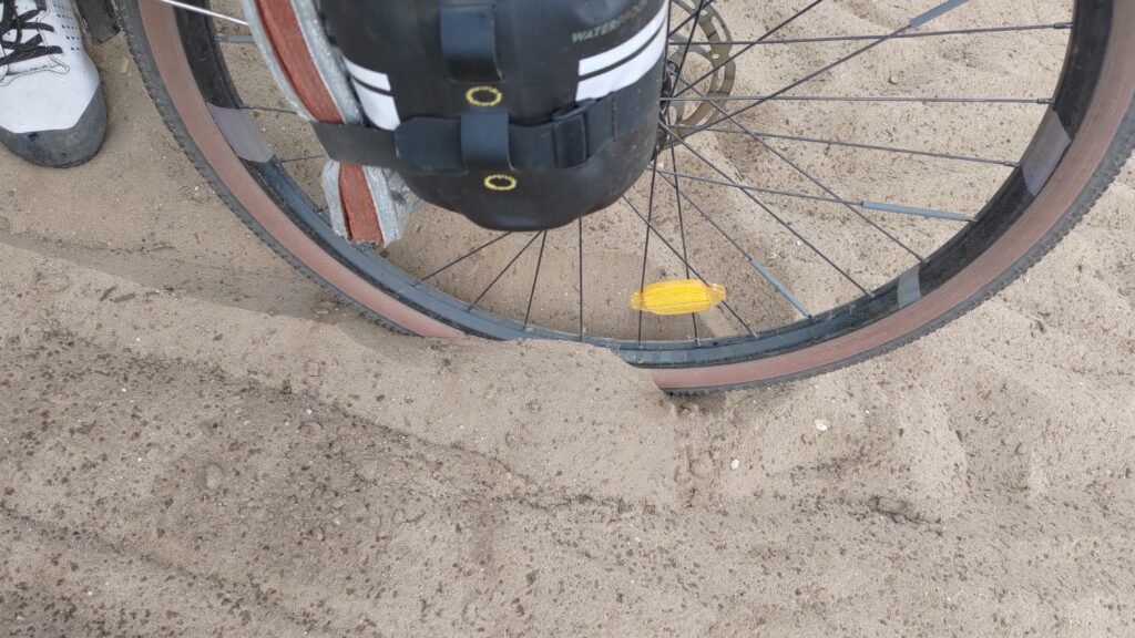 Pneu de vélo enfoncé dans le sable jusqu'à la jante