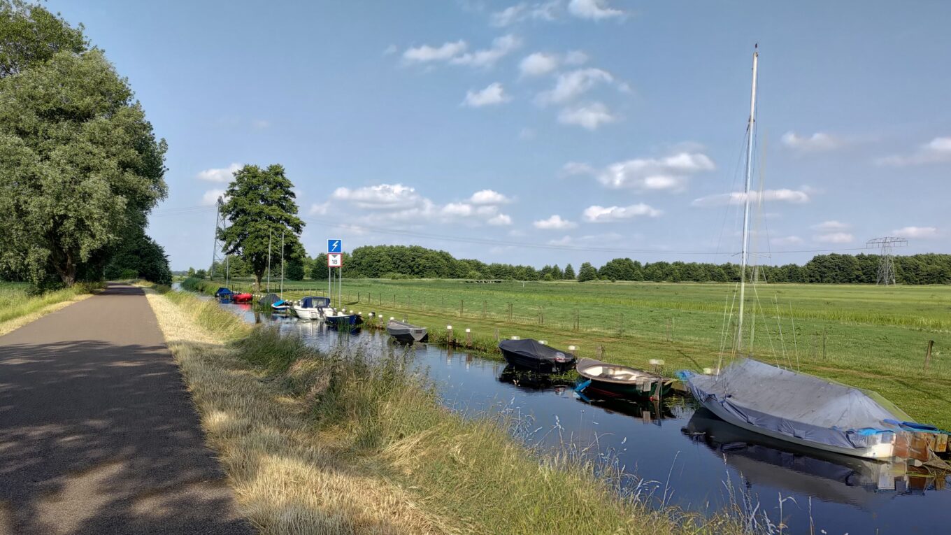 À gauche une piste cyclable, à droite un petit canal avec quelques bateaux amarrés