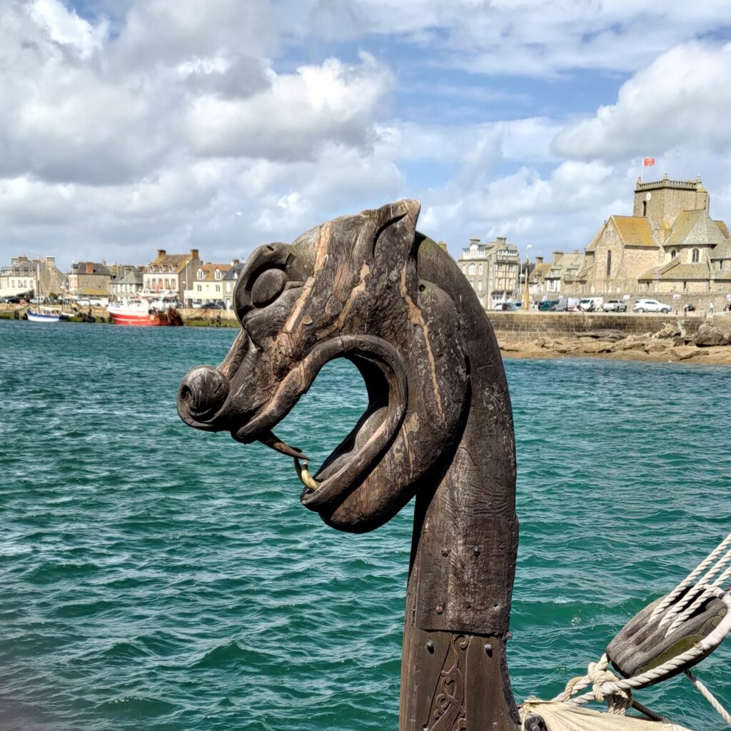 Figure dz prou d'un drakkar, en arrière plan le port et des bâtiments