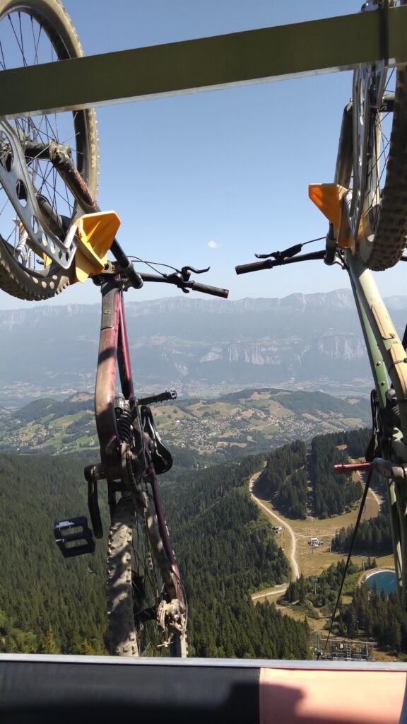 Deux VTT susoendus à un télésiège. Photo prise depuis le siège. En arrière plan la montagne (massif de la Chartreuse)