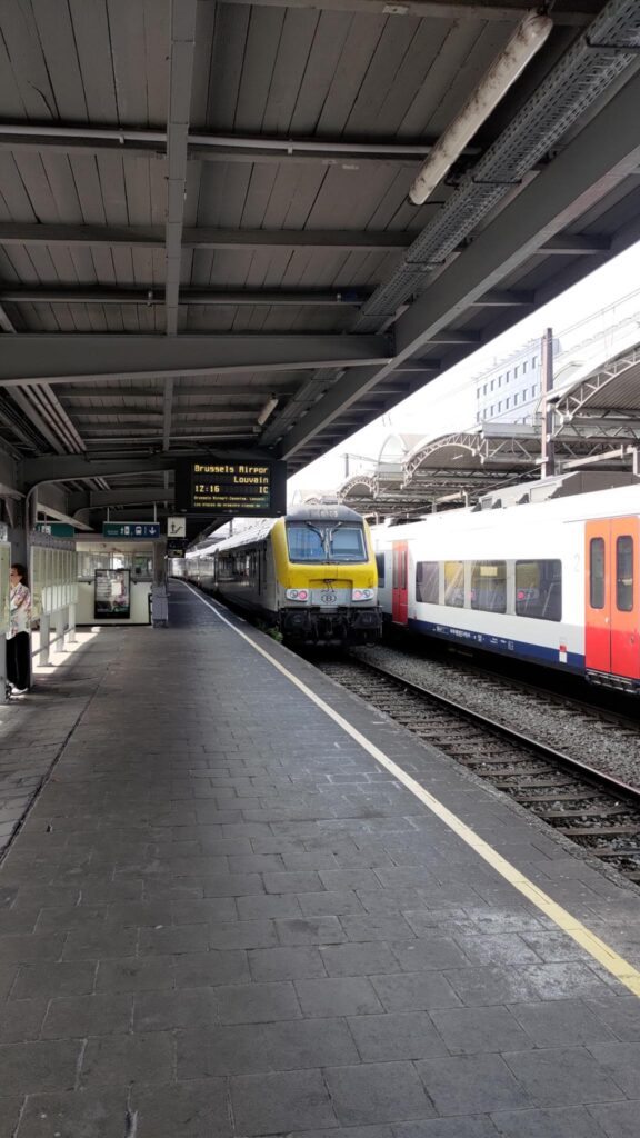 Quai de gare à Bruxelles-Midi, un train s'éloigne sur le quai.