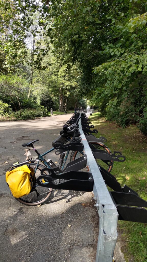 Alignement de nombreux rack à vélos vides dans un parc. Un seul vélo est accroché et suspendu dessus par le guidon