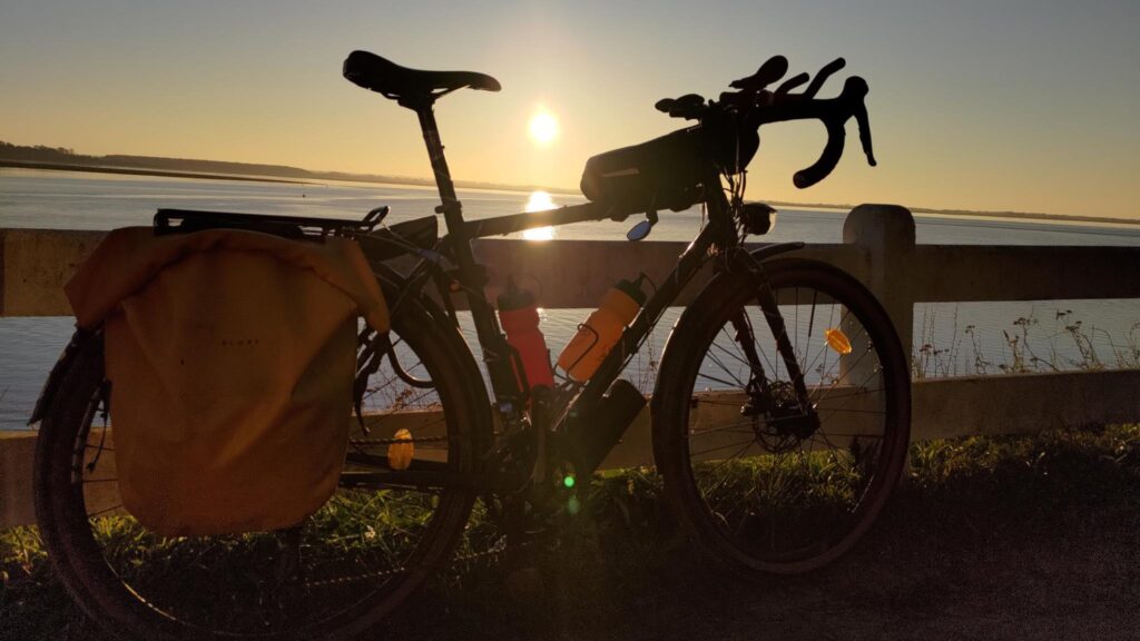 Un vélo posé sur une barrière en contre jour avec un couché de soleil derrière