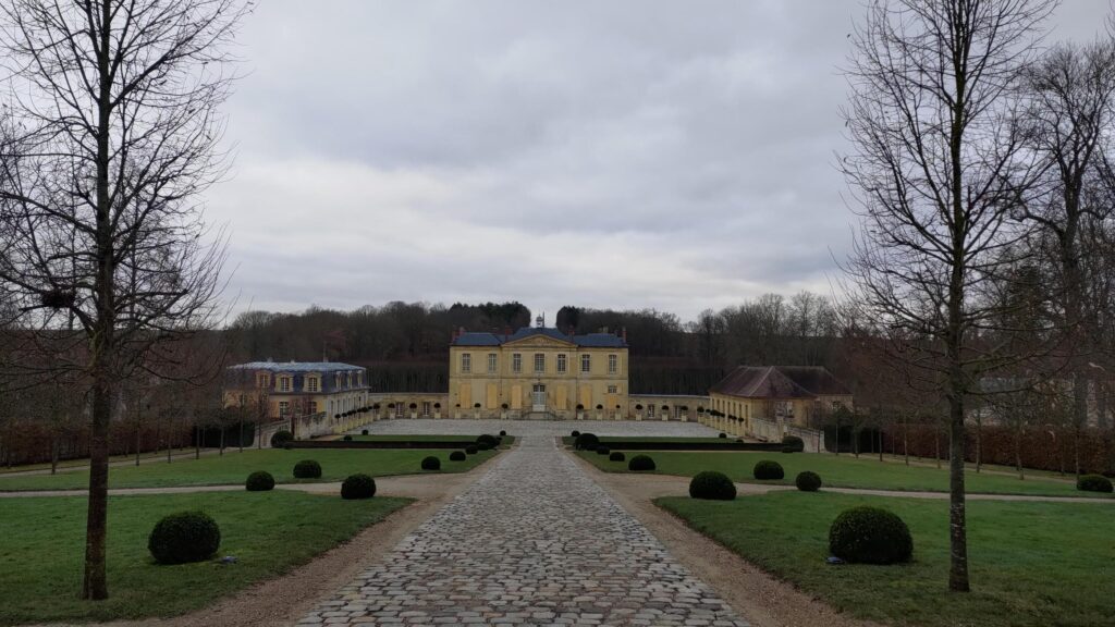 Chateau de Vilette vu depuis la grille. Une longue allée composée de gros pavée même à une grande cours constituée de la même façon. Centrée, le bâtiment principal reste modeste, tois corps de bâtiment sur deux étages. De part et d'autre dans la cours, deux autres bâtiments, l'un d'allure bourgeoise, l'autre très modeste, probablement d'anciennes écuries. L'herbe du jardin est taillée courte, ornementée en alignement de plusieurs boules de buis https://fr.wikipedia.org/wiki/Ch%C3%A2teau_de_Villette_(Cond%C3%A9court)