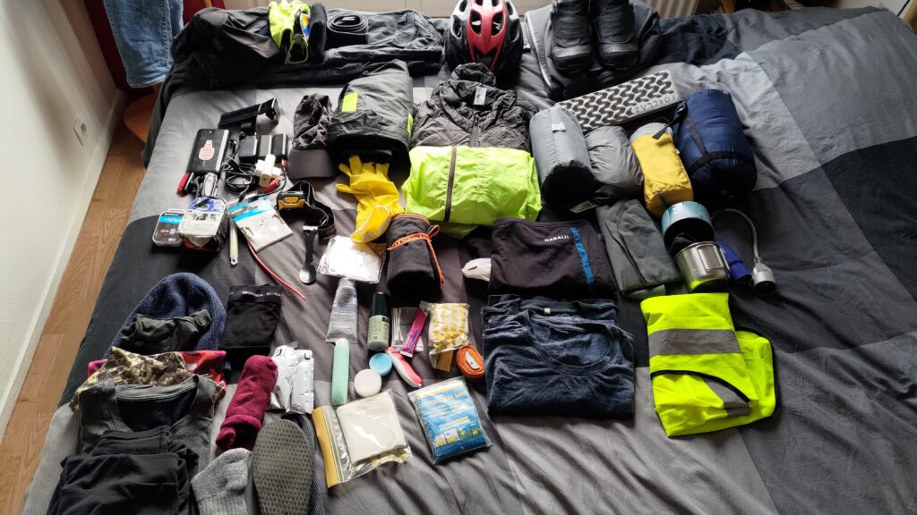 Plein d'affaires posées sur un lit en préparation d'un voyage vélo