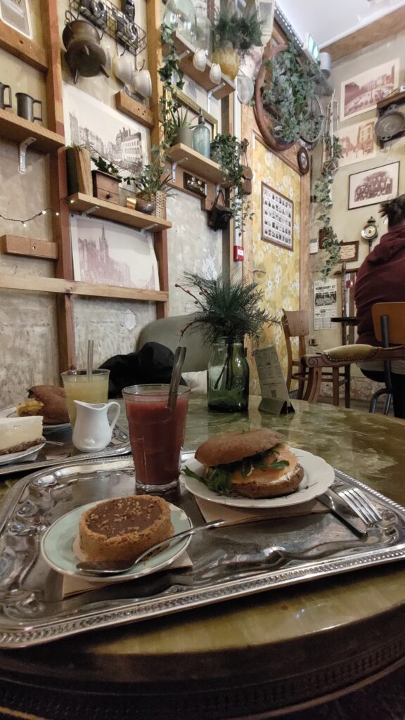 Plateau avec bagel jus de fruit et tartelette dans un décor de café très decinsteuit, murs bruts et déco type brocante