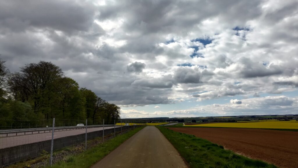 Piste cyclable le long d'une voie rapide et d'un champ
