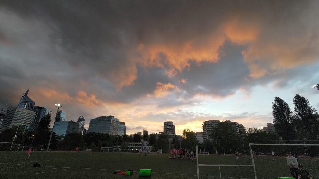 Couché de soleil sur l'ouest parisien, on voit nettement kes tours de la Défense. Le ciel est nuageux, couleurs orange gris jaune bleu
