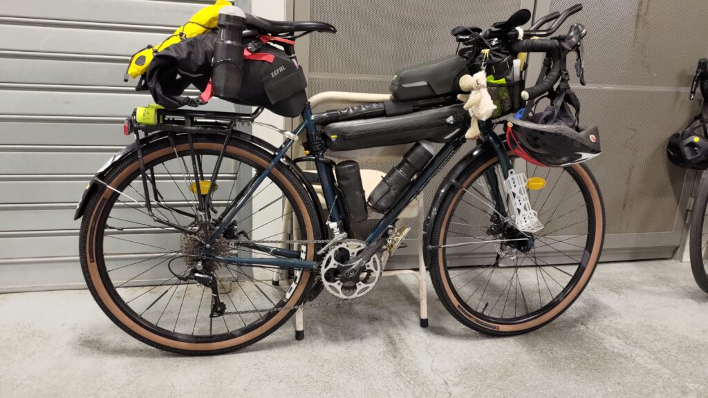 Vélo type gravel équipé bikepacking posé sur un rideau de fer