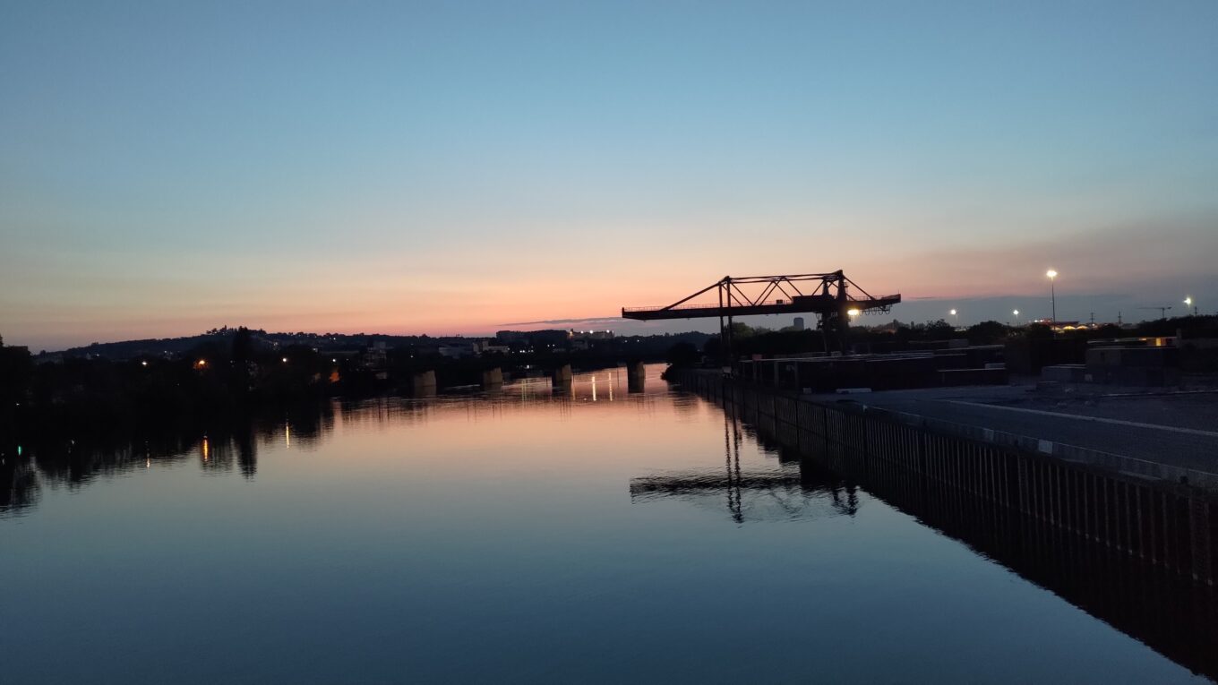 Levé de soleil sur la Seine vue vers le soleil depuis le pont de Genevilliers. Sur la droite une grosse structure métallique en contre jour. Elle se détache du reste de l'image en étant toute noire, alors que la Seine reflète un ciel aux couleurs marquées, du bleu dans le ciel au rose à l'horizon
