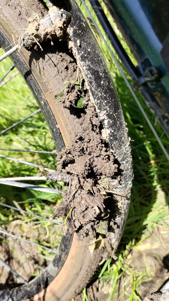 Vue d'une roue avant de vélo, pneu d'un gros diamètre couvert de boue et boue accumulée entre le pneu et le garde boue