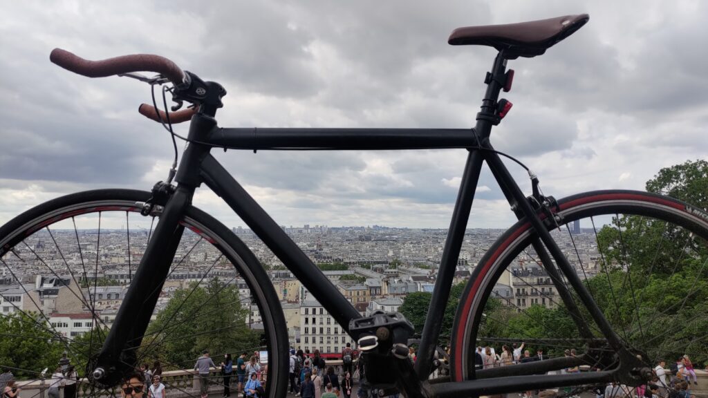 Vélo type single speed cadré très serré avec en arrière plan une large vue sur Paris depuis la butte Montmartre