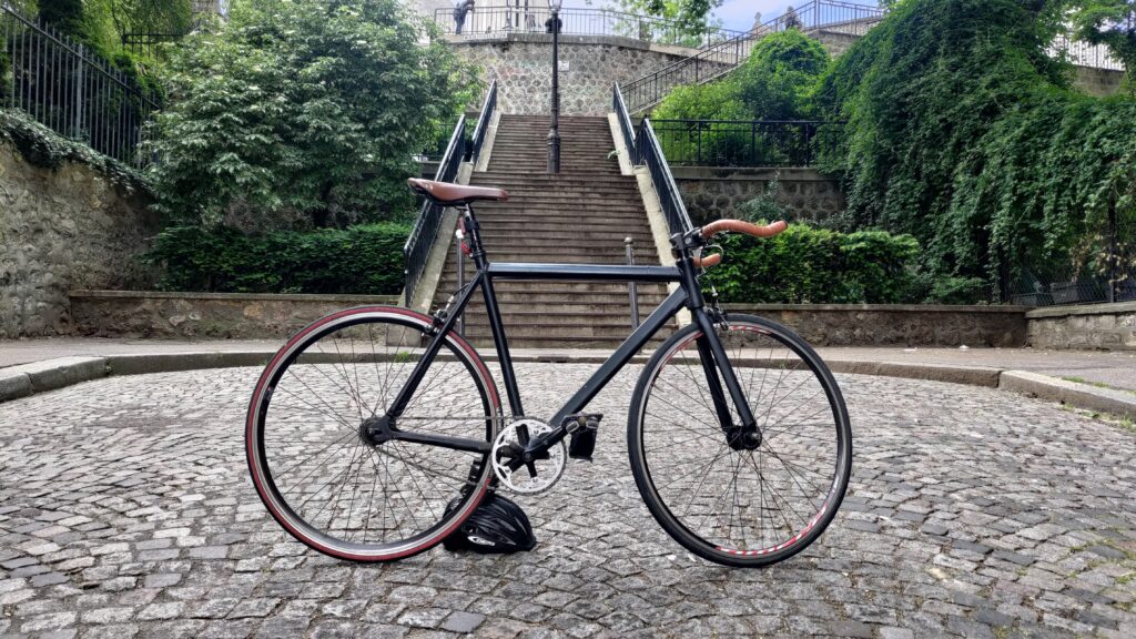 Vélo type single speed photographié devant un escalier à Paris quartier Montmartre