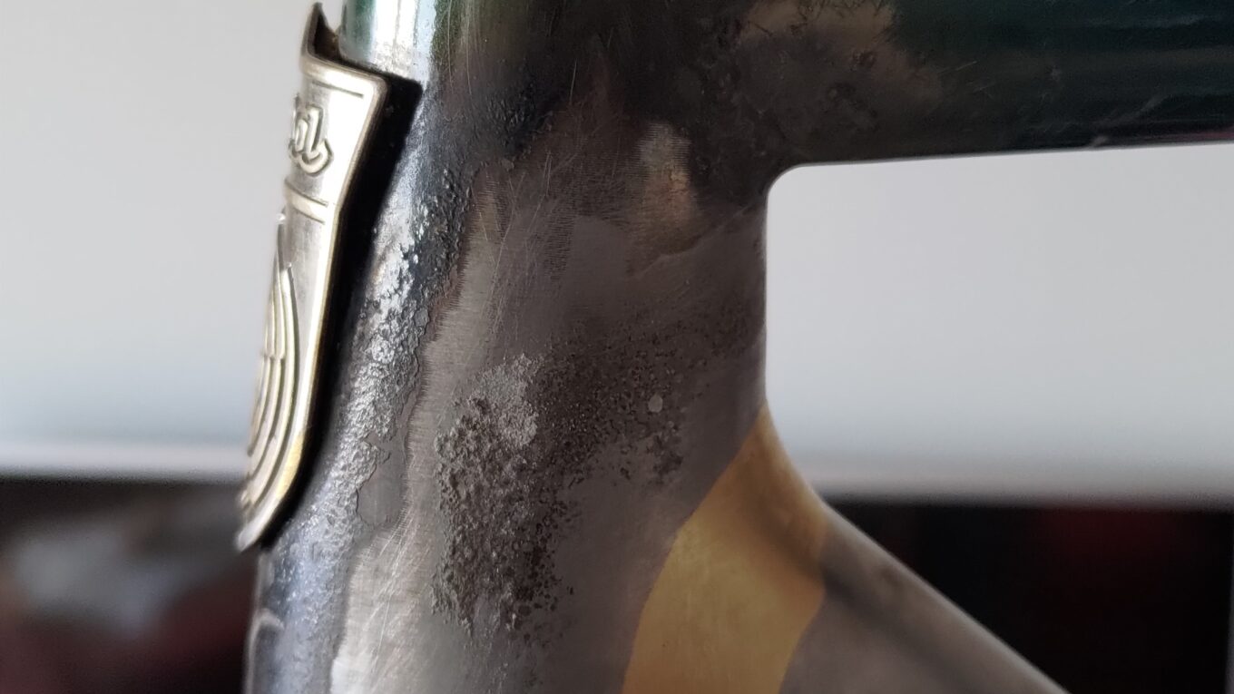Gros plan sur la soudure entre le tube diagonal et la douille de direction d'un cadre de vélo. La soudure est récente, pas de peinture sur le nouveau type et peinture écaillée par la chaleur sur l'ancien cadre