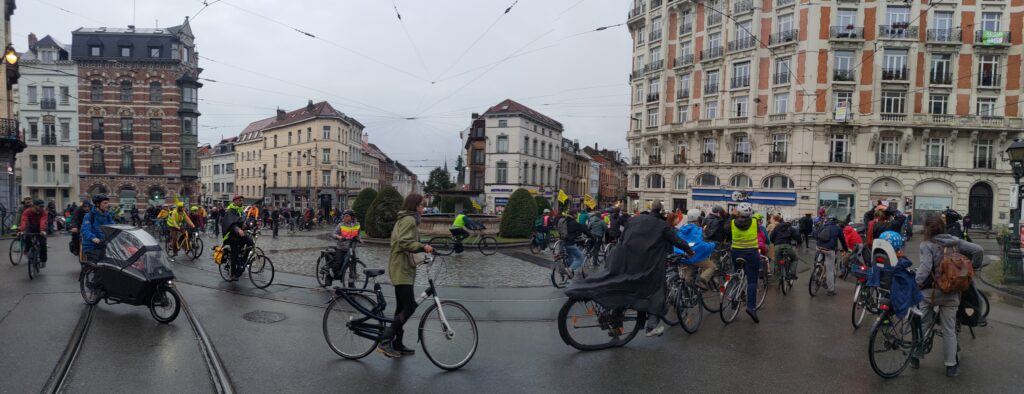 De très nombreux cyclistes autour d'une place, le ciel est gris