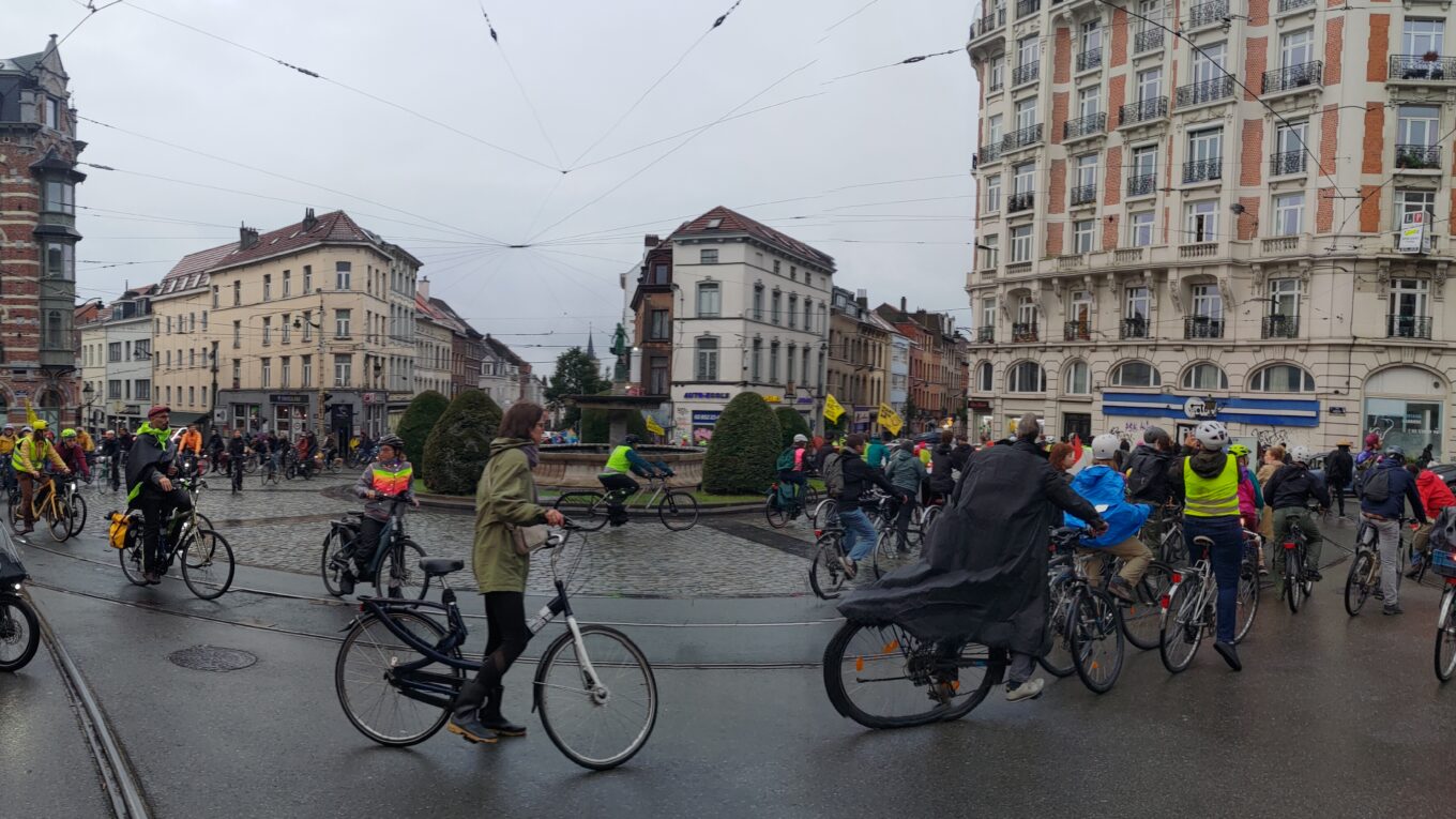 De très nombreux cyclistes autour d'une place, le ciel est gris