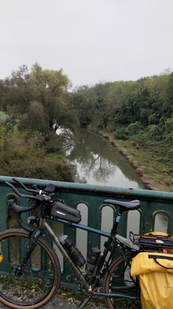 Vue vers une rivière depuis le haut d'un ancien pont de train wai premier plan sur la rambarde est posé un vélo