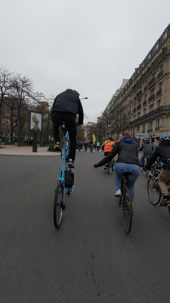 Deux personnes à vélo bavardant l'une avec l'autre, l'une est sur un tall bike