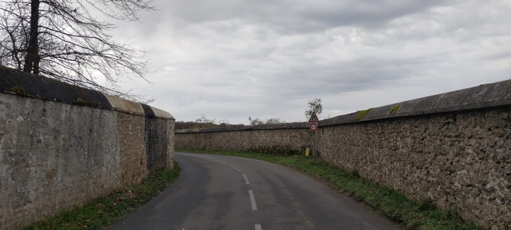 Une route et de part de d'autres de hauts murs de pierre d'une grand propriété