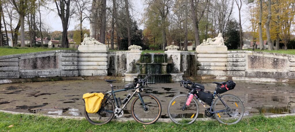 Deux vélos l'un face à l'autre, posés devant une ancienne fontaine