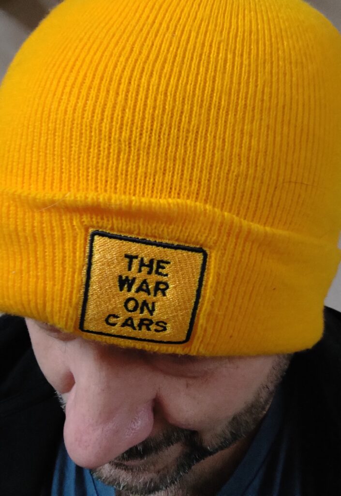 Gros plan sur une personne portant un bonnet jaune siglé "The war on cars"