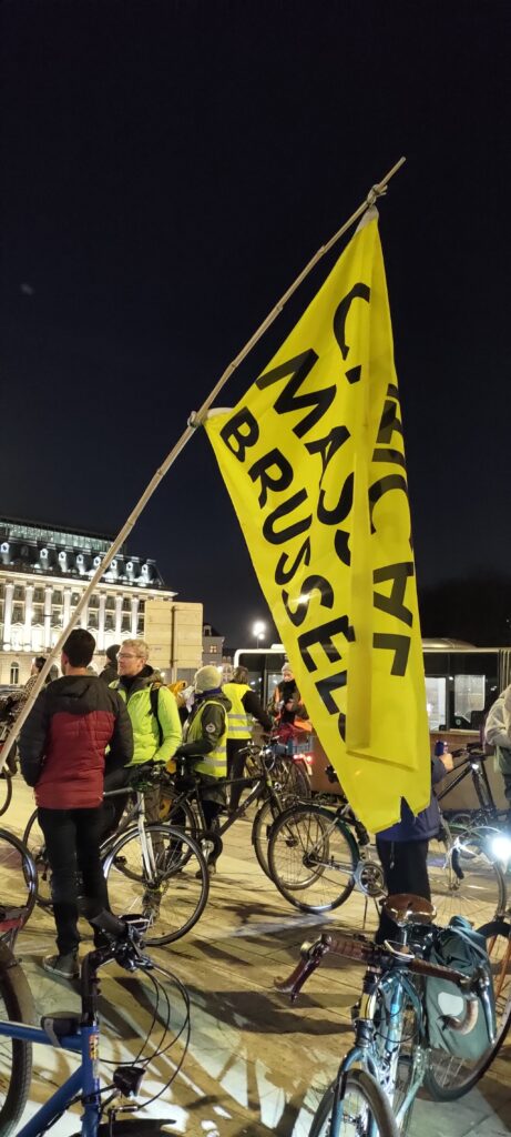 Le drapeau de la Critical Mass Brussels flottant de nuit devant la foule
