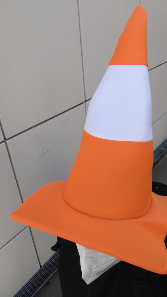 Une personne avec un chapeau en forme de cône de chantier en mousse aux couleurs orange et blanche