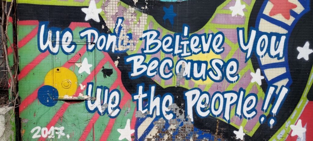 sur un fond bariolé très coloré teste "We don't believe you because we the people"