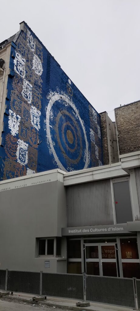 sur un pignon de mur d'un immeuble parisien, une immense fresque de style arabe. Dessous entrée moderne d'un bâtiment "Institut des Cultures d'Islam"