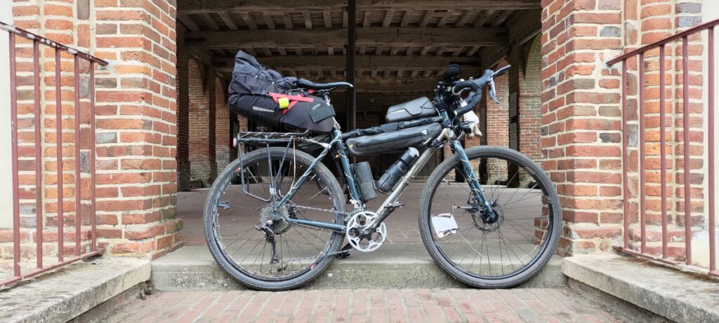 Vélo type gravel chargé en bagage à l'entrée du hall en brique