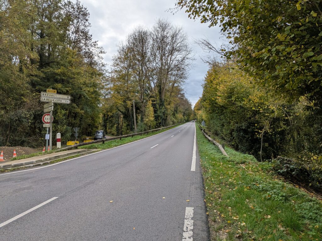 Grosse départementale qui monte à travers la forêt, le panneau de circulation indique la ville au sommet "La Belle Côte, 1,5km"