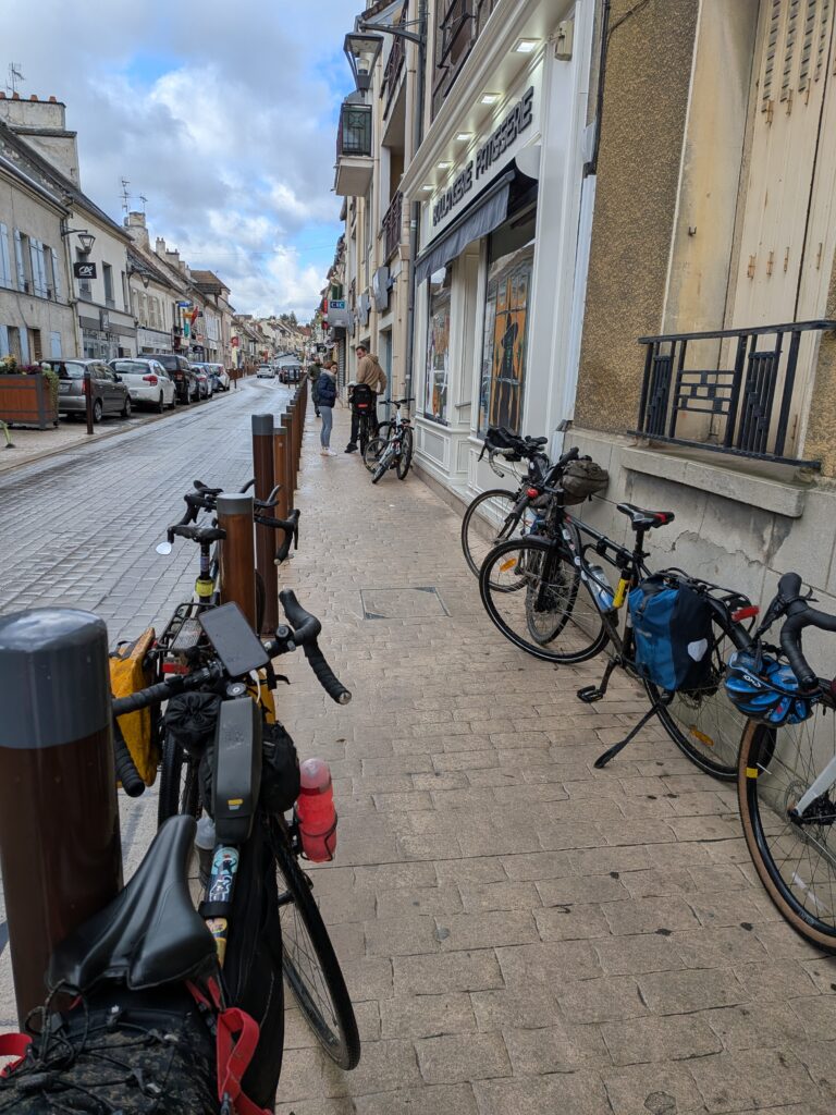Plusieurs vélos posés sur un trottoir devant une boulangerie