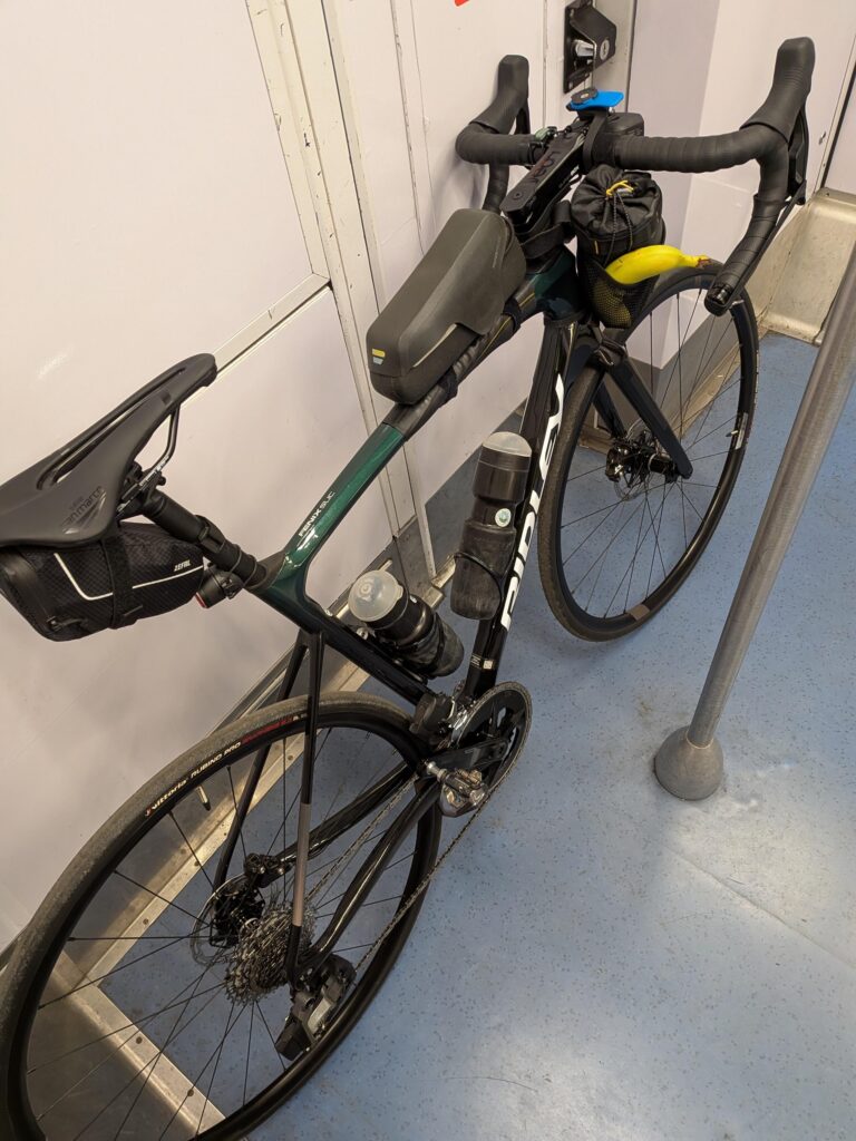 Un vélo type course posé dans le RER B, deux bidons et une banane qui dépasse du food pouch