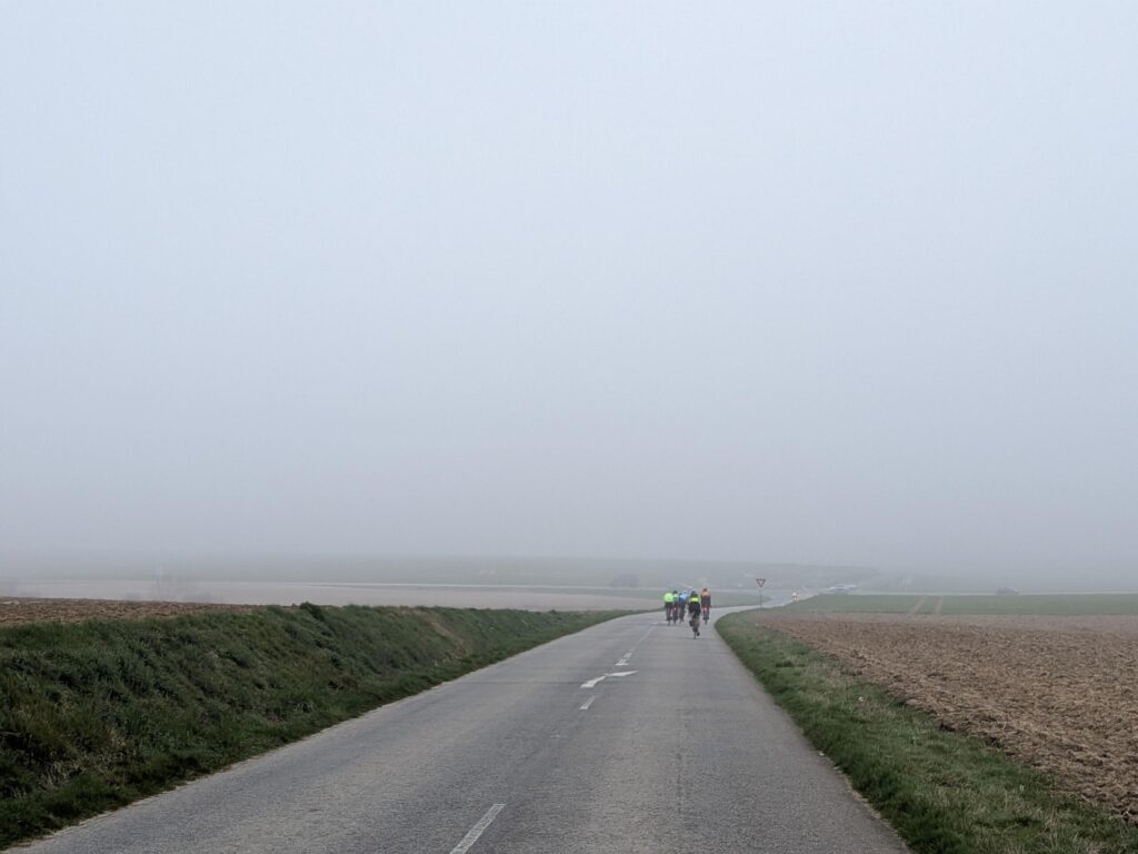 Route de campagne avec une brume légère avec un groupe de cyclistes