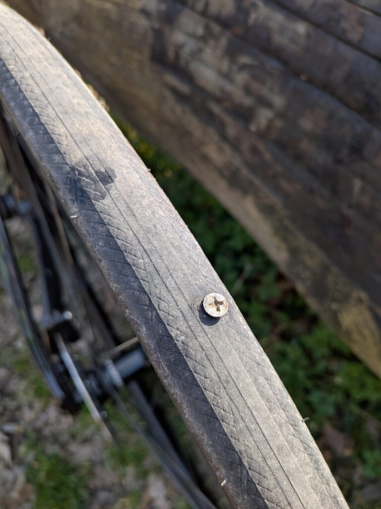 Une vis en gros plan plantée dans un pneu de vélo