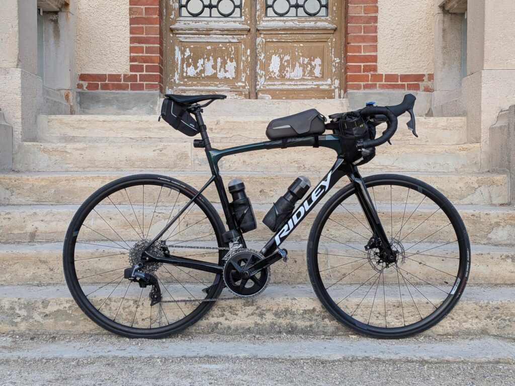 Un vélo type course vu de profil et appuyé sur l'entrée en pierre d'une maison