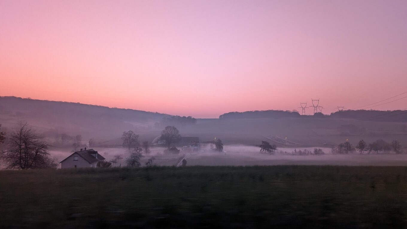 Au petit matin, un ciel rose, paysage de campagne avec une brume qui est très présente et concentrée dans la vallée