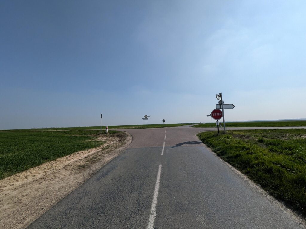 Arrivée à un carrefour de deux routes perpendiculaires. De nombreux panneaux sont présents donc un stop dans l'axe de déplacement
