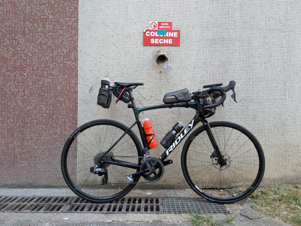Un vélo de course posé le long d'un mur d'immeuble en mosaïque