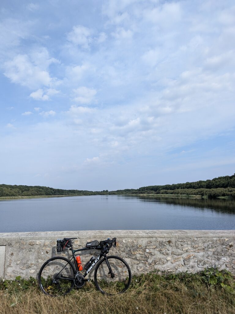 Un vélo de course posé sur un muret devant un grand étang