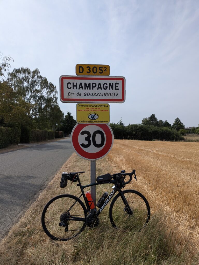 Un vélo de course posé sur un poteau portant un panneau de ville "Champagne"