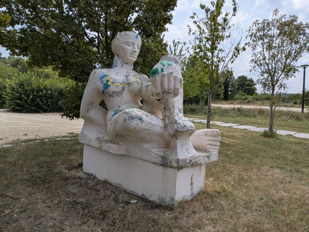 Une statue en pierre blanche couverte partiellement de tâches de peinture