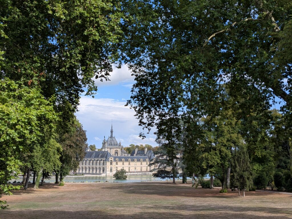 Vue du château de Chantilly à travers les arbres