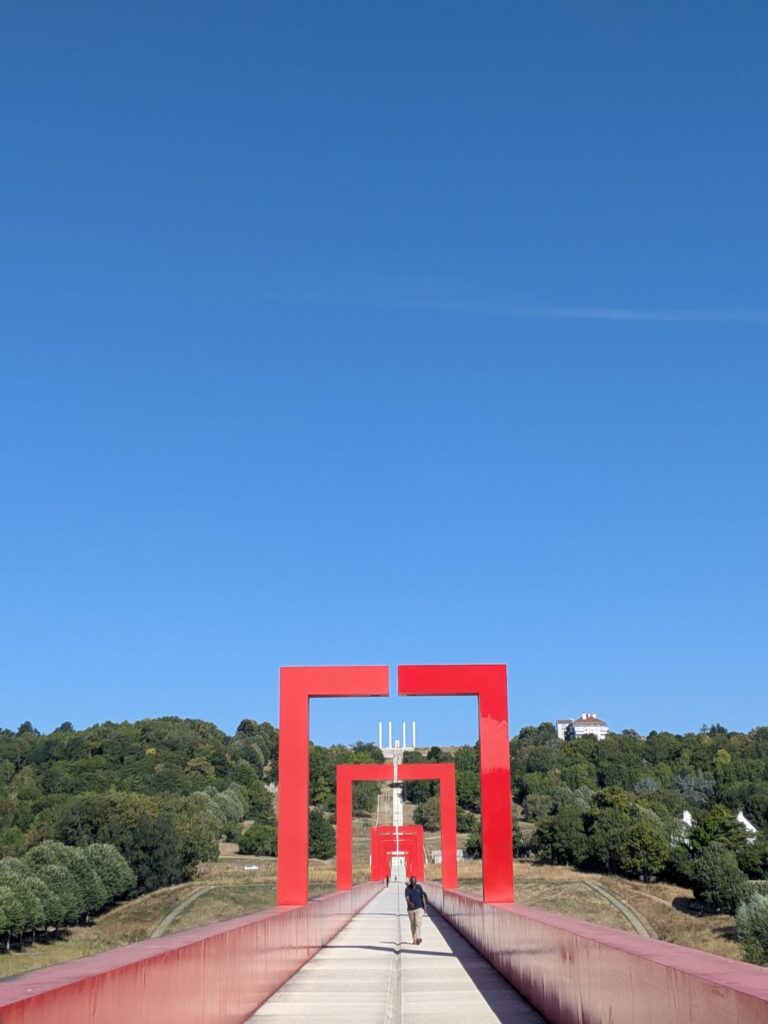 Vue de l'axe majeur à Cergy Pontoise, des arches rouges qui sont toutes alignées au dessus d'un chemin