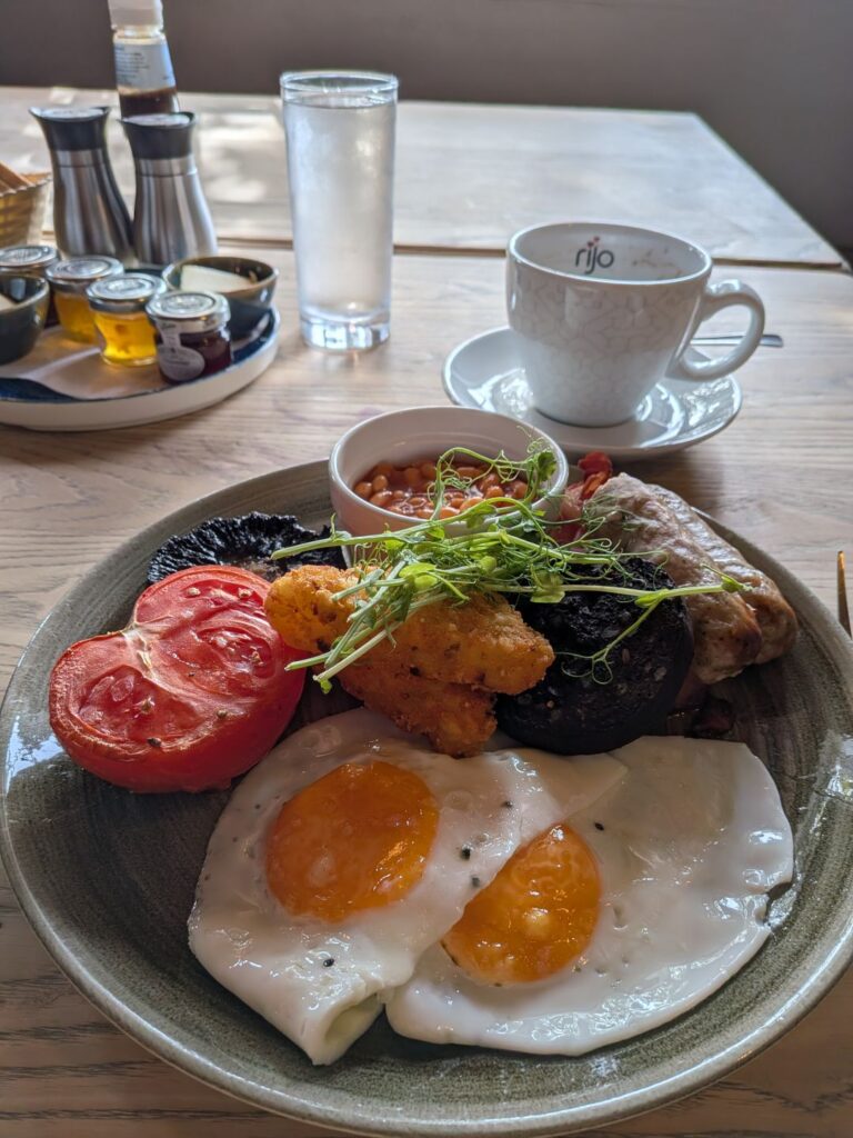 Une assiette de petit déjeuner typiquement anglais (tomates, œufs, boudin noir, haricots rouges, etc) et une tasse de thé