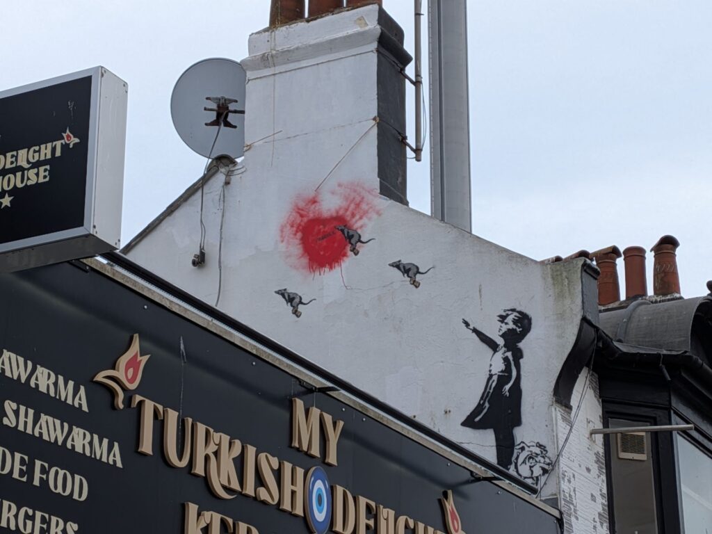 Graph de type Banksy d'une petite fille qui semble faire un salut bras droit tendu et un bulldog à ses pieds, des rats "volants" sont dans le prolongement du bras et sont vers une tâche rouge pouvant être un cœur