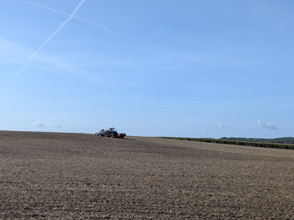 Un gros tracteur en train de travail au milieu d'un champs labouré