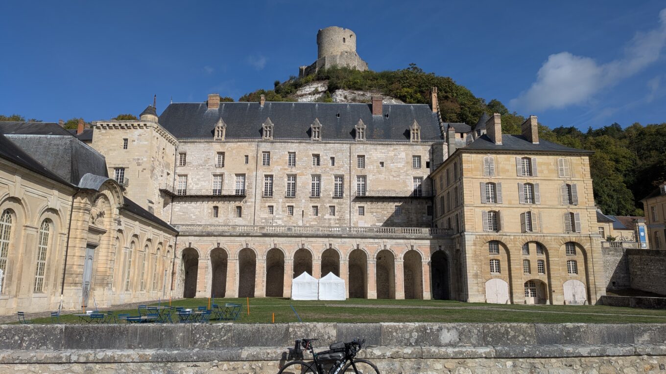 Un vélo posé devant le château de la Roche-Guyon et une tour en ruine au sommet d'une colline derrière